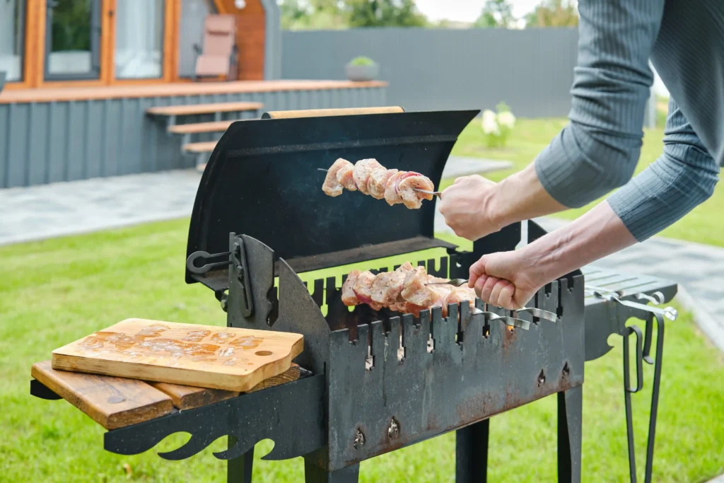 Home cook placing marinated pork skewers on a grill