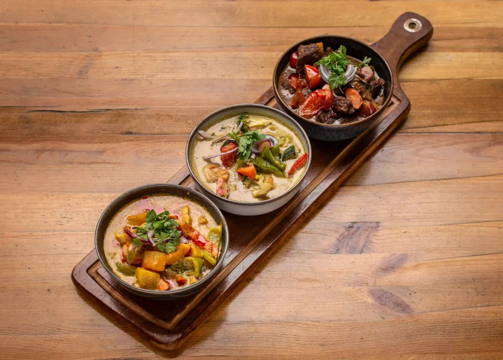 Thai yellow, green, and red curries served on a wooden platter
